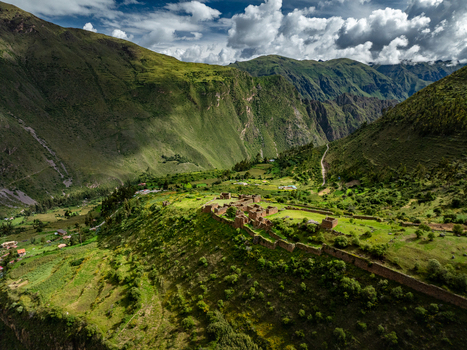 Aerial view of Pumamarca Ruins in the Sacred Valley with stone structures lush green mountain slopes and rural landscape in Pallata Qosqo Peru.