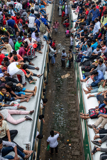 Dhaka Bangladesh 15 June 2018 View of Airport Railway Station with hundreds of people sitting on the roofs of two trains during the Eid al Fitr holiday rush. Dhaka Bangladesh 15 June 2018 View of Airport Railway Station with hundreds of people sitting on the roofs of two trains during the Eid al Fitr holiday rush.