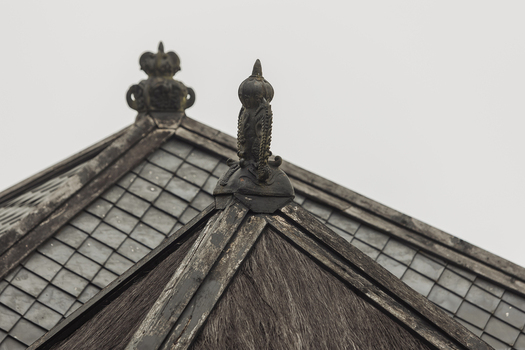 View of the ornate roof finials and weathered shingles of Cetho Temple under an overcast sky in Kecamatan Jenawi Jawa Tengah Indonesia. View of the ornate roof finials and weathered shingles of Cetho Temple under an overcast sky in Kecamatan Jenawi Jawa Tengah Indonesia.