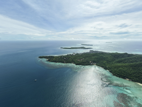Aerial view of the coastline where the deep blue sea meets the white sandy beach and lush green forest Karimunjawa Central Java Indonesia.