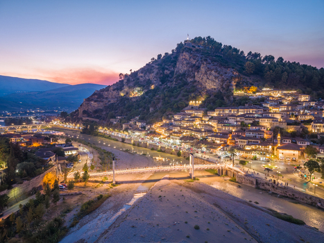 Aerial view of the historic town of Berat with traditional white houses illuminated streets and the ancient castle perched on the hill above the Osum River in Berat Berat County Albania.