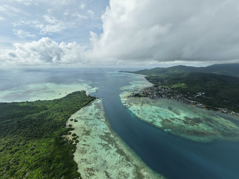 Aerial view of the turquoise waters embrace the lush green islands meeting at the horizon under a sky brushed with clouds Karimunjawa Central Java Indonesia. Aerial view of the turquoise waters embrace the lush green islands meeting at the horizon under a sky brushed with clouds Karimunjawa Central Java Indonesia.