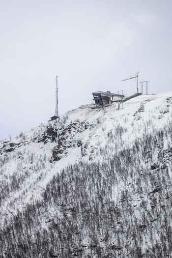 View of the Fjellheisen cable car upper station on the snowy slopes of Mount Storsteinen with a communication tower and construction crane Tromso Troms Norway. View of the Fjellheisen cable car upper station on the snowy slopes of Mount Storsteinen with a communication tower and construction crane Tromso Troms Norway.
