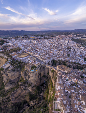 Aerial view of the historic town of Ronda featuring the iconic Puente Nuevo bridge spanning the deep El Tajo gorge surrounded by white washed buildings in Ronda Andalusia Spain. Aerial view of the historic town of Ronda featuring the iconic Puente Nuevo bridge spanning the deep El Tajo gorge surrounded by white washed buildings in Ronda Andalusia Spain.