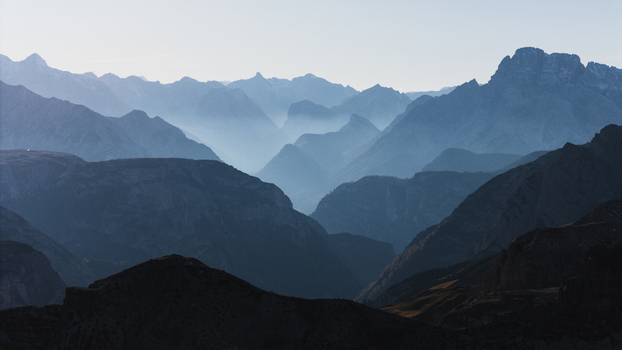 Aerial view of layered silhouettes of mountain peaks and misty valleys in the Tre Cime di Lavaredo area Dolomites Italy. Aerial view of layered silhouettes of mountain peaks and misty valleys in the Tre Cime di Lavaredo area Dolomites Italy.