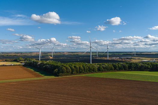 Aerial view of Chelveston Renewable Energy and BESS site featuring wind turbines and solar panels surrounded by agricultural fields and trees in Chelveston England United Kingdom. Aerial view of Chelveston Renewable Energy and BESS site featuring wind turbines and solar panels surrounded by agricultural fields and trees in Chelveston England United Kingdom.
