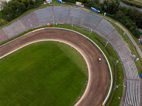 Gdansk Poland 19 September 2026 Aerial view of a speedway stadium with a dirt track green grass infield and tiered seating rows under a cloudy sky. Gdansk Poland 19 September 2026 Aerial view of a speedway stadium with a dirt track green grass infield and tiered seating rows under a cloudy sky.