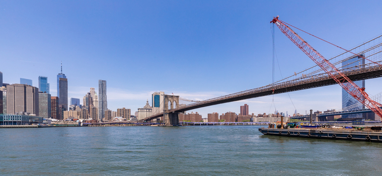View of the Brooklyn Bridge with a construction barge and crane on the East River featuring the Manhattan skyline in the background New York New York United States. View of the Brooklyn Bridge with a construction barge and crane on the East River featuring the Manhattan skyline in the background New York New York United States.