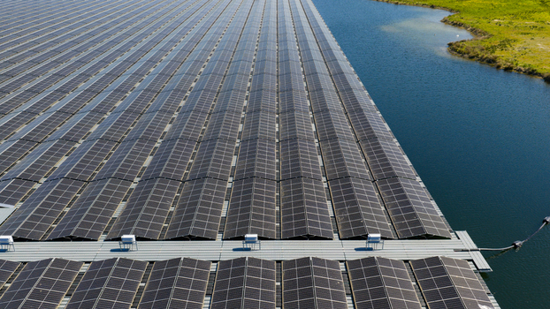 Aerial view of a massive floating solar farm with rows of photovoltaic panels on a calm lake surface next to a green grassy bank Zwolle Overijssel Netherlands. Aerial view of a massive floating solar farm with rows of photovoltaic panels on a calm lake surface next to a green grassy bank Zwolle Overijssel Netherlands.