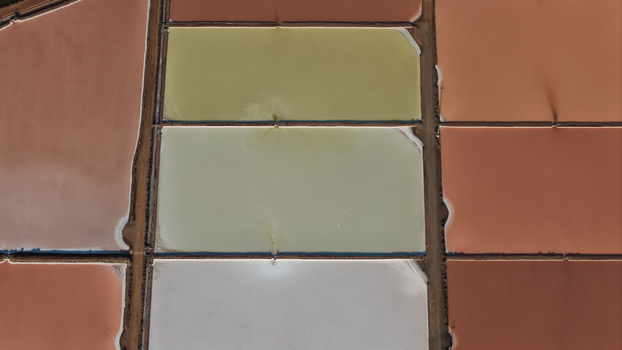 Aerial view of multicolored salt evaporation ponds separated by narrow dirt paths in Cagliari Sardinia Italy. Aerial view of multicolored salt evaporation ponds separated by narrow dirt paths in Cagliari Sardinia Italy.