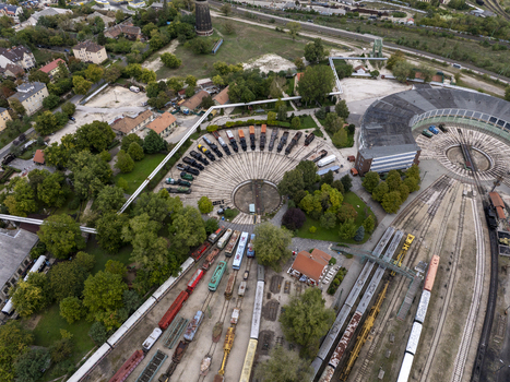 Aerial view of the Hungarian Railway Museum in Budapest featuring a historic roundhouse with vintage locomotives on tracks surrounded by trees and urban infrastructure in Budapest Hungary. Aerial view of the Hungarian Railway Museum in Budapest featuring a historic roundhouse with vintage locomotives on tracks surrounded by trees and urban infrastructure in Budapest Hungary.