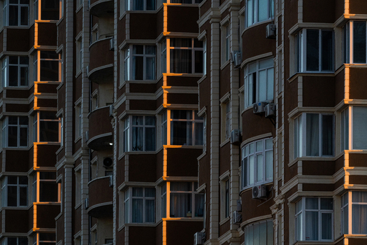 View of the modern apartment building facade with repetitive windows and balconies illuminated by warm golden hour light in Aktau Mangystau Region Kazakhstan.