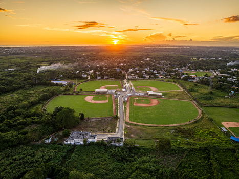 Aerial view of Quality Baseball Academy with multiple baseball fields green grass and dirt diamonds under a golden hour sunset in San Antonio de Guerra Santo Domingo Provinc Dominican Republic. Aerial view of Quality Baseball Academy with multiple baseball fields green grass and dirt diamonds under a golden hour sunset in San Antonio de Guerra Santo Domingo Provinc Dominican Republic.