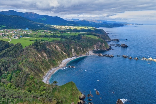Aerial view of Silence Beach Viewpoint with rugged cliffs turquoise water and lush green hills in Cudillero Asturias Spain.