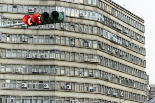 View of a red traffic light in front of a large residential building with numerous windows and air conditioning units Taipei City Taiwan. View of a red traffic light in front of a large residential building with numerous windows and air conditioning units Taipei City Taiwan.