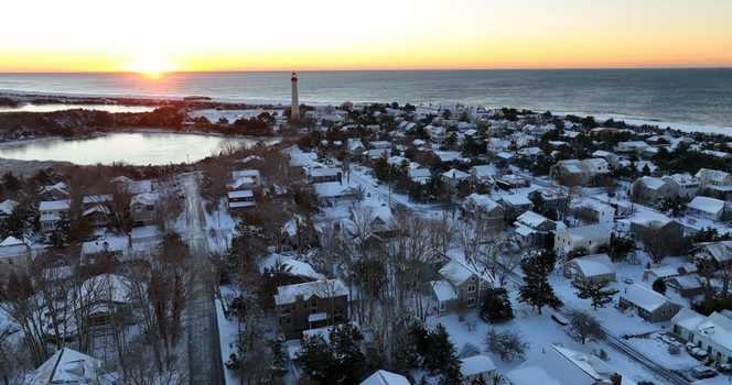 Aerial view of the snow covered Cape May Lighthouse and surrounding coastal town during a golden sunrise in Cape May New Jersey United States.
