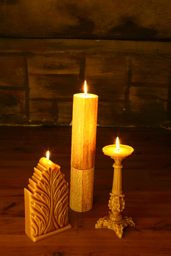View of three lit candles of different shapes and sizes on a wooden surface in Lahore Punjab Pakistan.