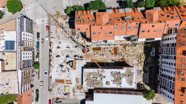 Aerial view of a construction site with a crane and building foundations surrounded by residential blocks with orange roofs in Pancevo Vojvodina Serbia.