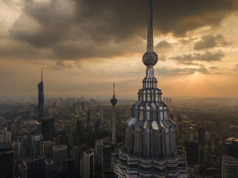 Kuala Lumpur Malaysia 11 March 2026 Aerial view of the Petronas Twin Towers spire and the city skyline with the KL Tower under a dramatic sunset sky.
