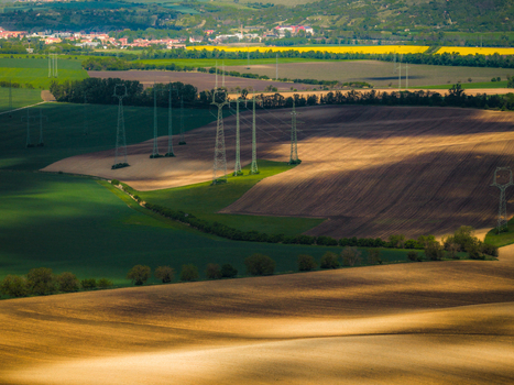 Aerial view of rolling agricultural fields with power lines casting shadows across the landscape in Brno South Moravian Region Czechia.
