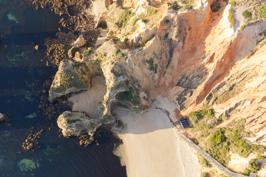 Aerial view of the golden sandstone cliffs and sandy beach along the coastline of Lagos Faro District Portugal.