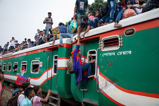 Dhaka Bangladesh 15 June 2018 View of Airport Railway Station with a crowded train where people are sitting on the roof and a woman is climbing aboard during Eid al Fitr rush. Dhaka Bangladesh 15 June 2018 View of Airport Railway Station with a crowded train where people are sitting on the roof and a woman is climbing aboard during Eid al Fitr rush.