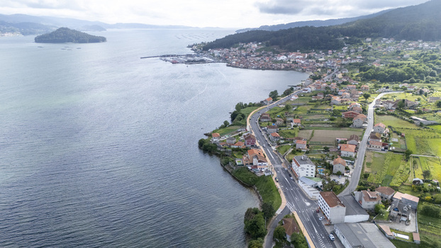 Aerial view of the coastal town featuring traditional houses green fields and a winding road along the blue waters of the bay Casalvito Pontevedra Spain. Aerial view of the coastal town featuring traditional houses green fields and a winding road along the blue waters of the bay Casalvito Pontevedra Spain.