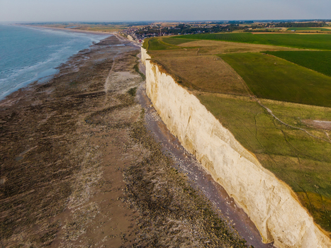 Aerial view of the Beach of the Bois de Cise featuring dramatic white chalk cliffs and green agricultural fields along the coastline in Ault Hauts de France France.