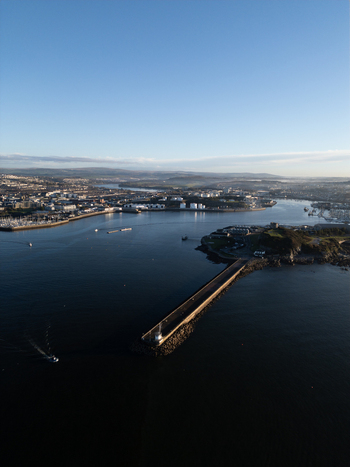 Aerial view of Plymouth Sound featuring the Mount Batten breakwater and the industrial waterfront under a clear blue sky in Plymouth Devon United Kingdom.