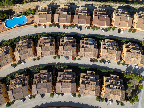 Aerial view of a residential complex with terracotta tiled roofs a swimming pool and parked cars in Moraira Valencian Community Spain.