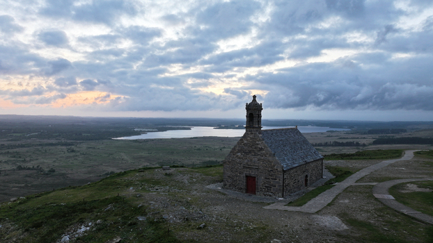 Aerial view of Chapelle Saint Michel de Brasparts on a hilltop overlooking the Lac de Saint Michel under a cloudy sky at dusk in Saint Rivoal Bretagne France. Aerial view of Chapelle Saint Michel de Brasparts on a hilltop overlooking the Lac de Saint Michel under a cloudy sky at dusk in Saint Rivoal Bretagne France.