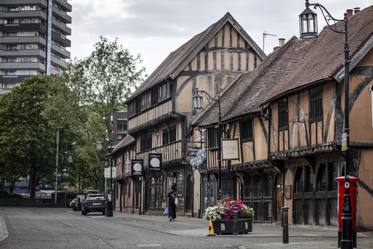 Coventry England United Kingdom 20 July 2026 View of historic timber framed buildings along Spon Street with flower planters a red post box and a modern high rise in the background.