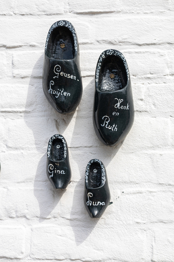 View of decorative black wooden clogs with names painted on them mounted on a white brick wall in Thorn Limburg Netherlands. View of decorative black wooden clogs with names painted on them mounted on a white brick wall in Thorn Limburg Netherlands.