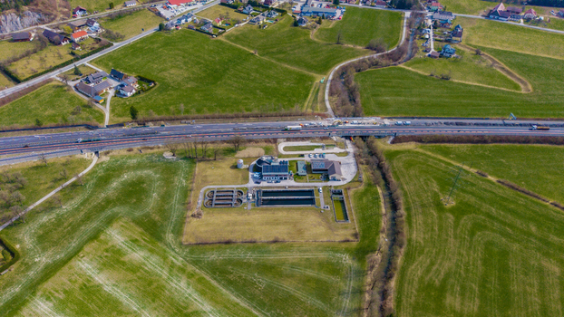 Aerial view of a wastewater treatment plant amidst vibrant green fields under a clear sky bisected by a bustling highway Windischgarsten Upper Austria Austria. Aerial view of a wastewater treatment plant amidst vibrant green fields under a clear sky bisected by a bustling highway Windischgarsten Upper Austria Austria.