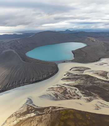Aerial view of Ljotipollur crater lake with its vibrant turquoise water surrounded by dark volcanic slopes and braided river channels in the highlands Rangarthing ytra Iceland. Aerial view of Ljotipollur crater lake with its vibrant turquoise water surrounded by dark volcanic slopes and braided river channels in the highlands Rangarthing ytra Iceland.