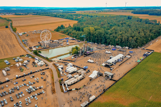 Herzogenaurach Germany 22 July 2022 Aerial view of the Open Beatz Festival featuring a Ferris wheel stages and crowds of people amidst fields and forests. Herzogenaurach Germany 22 July 2022 Aerial view of the Open Beatz Festival featuring a Ferris wheel stages and crowds of people amidst fields and forests.