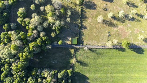 Aerial view of a square green water tank beside a rural road surrounded by lush forest and agricultural fields in Ourense Province of Ourense Spain. Aerial view of a square green water tank beside a rural road surrounded by lush forest and agricultural fields in Ourense Province of Ourense Spain.