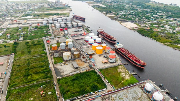 Aerial view of Satellite Town oil terminal with large storage tanks and cargo ships docked along the river in Lagos LAGOS Nigeria.