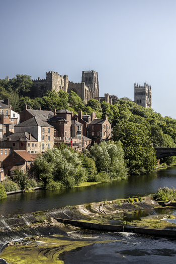 View of the historic Durham Cathedral and Durham Castle perched on a wooded hillside above the River Wear in Durham England United Kingdom. View of the historic Durham Cathedral and Durham Castle perched on a wooded hillside above the River Wear in Durham England United Kingdom.
