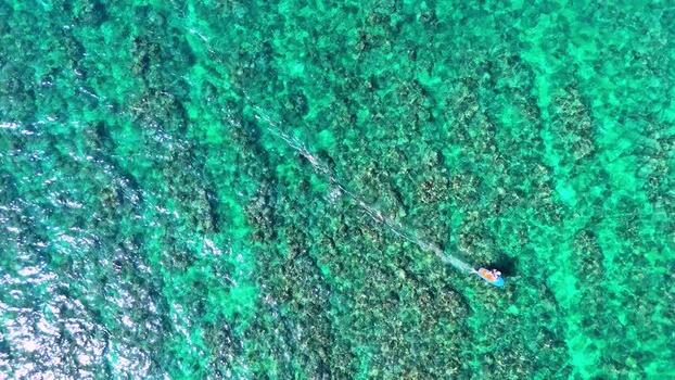 Aerial view of a man riding an e foil over a reef and blue water United States.United States. Aerial view of a man riding an e foil over a reef and blue water United States.United States.