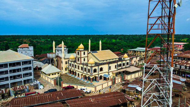 Aerial view of a majestic mosque with golden domes contrasting with rusty roofs and a communication mast against a verdant backdrop Igbaja Nigeria. Aerial view of a majestic mosque with golden domes contrasting with rusty roofs and a communication mast against a verdant backdrop Igbaja Nigeria.
