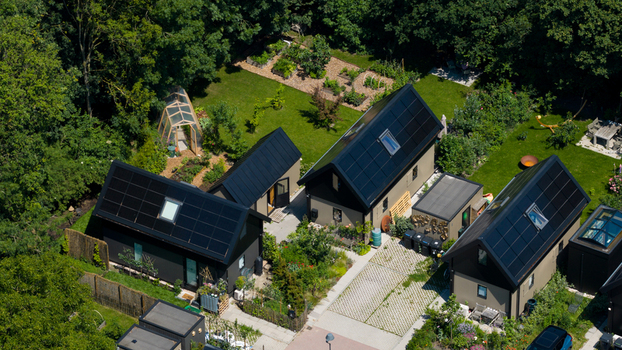 Aerial view of Ecodorp Bolderburen featuring modern sustainable houses with black roofs and solar panels surrounded by lush gardens and vegetable patches in Almere Flevoland Netherlands. Aerial view of Ecodorp Bolderburen featuring modern sustainable houses with black roofs and solar panels surrounded by lush gardens and vegetable patches in Almere Flevoland Netherlands.
