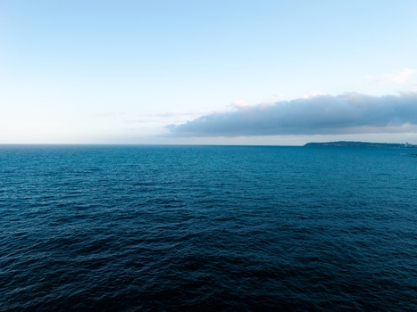 Aerial view of the deep blue ocean with a distant coastline and clouds on the horizon in Dee Why New South Wales Australia. Aerial view of the deep blue ocean with a distant coastline and clouds on the horizon in Dee Why New South Wales Australia.