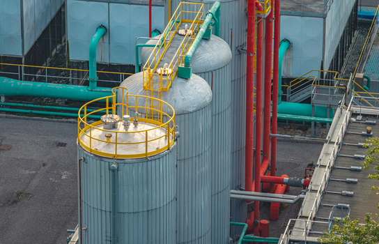 Aerial view of large industrial storage tanks pipelines and cooling infrastructure in a heavy manufacturing production complex in Brescia Lombardy Italy.