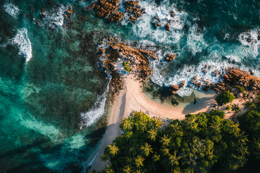 Aerial view of Secret Beach Mirissa with turquoise waters rocky coastline and lush palm trees surrounding the sandy shore Mirissa Southern Province Sri Lanka. Aerial view of Secret Beach Mirissa with turquoise waters rocky coastline and lush palm trees surrounding the sandy shore Mirissa Southern Province Sri Lanka.