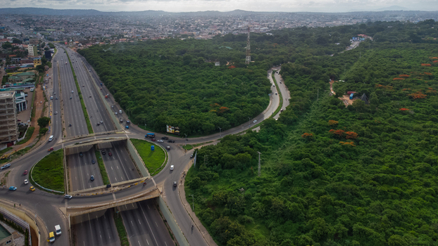 Accra Ghana 02 June 2023 Aerial view of Forever roundabout featuring a multi level highway interchange surrounded by dense green forest and urban sprawl under a cloudy sky. Accra Ghana 02 June 2023 Aerial view of Forever roundabout featuring a multi level highway interchange surrounded by dense green forest and urban sprawl under a cloudy sky.