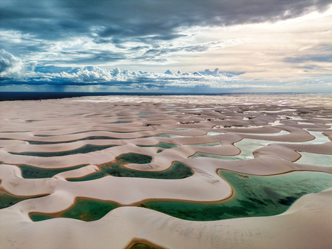Aerial view of Lagoa Bonita featuring white sand dunes and turquoise rainwater lagoons under a dramatic cloudy sky in Barreirinhas State of Maranhao Brazil. Aerial view of Lagoa Bonita featuring white sand dunes and turquoise rainwater lagoons under a dramatic cloudy sky in Barreirinhas State of Maranhao Brazil.