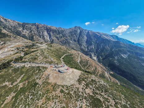 Aerial view of the Llogara Pass winding through the rugged Ceraunian Mountains with a scenic viewpoint lush green slopes and clear blue sky in Llogara Vlore County Albania. Aerial view of the Llogara Pass winding through the rugged Ceraunian Mountains with a scenic viewpoint lush green slopes and clear blue sky in Llogara Vlore County Albania.