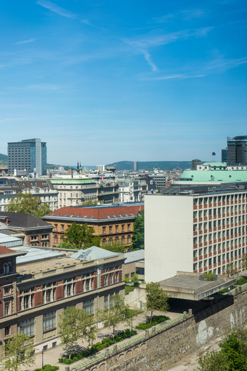Aerial view of historic and modern architecture with rooftops green trees and a clear blue sky over the urban landscape in Vienna Vienna Austria. Aerial view of historic and modern architecture with rooftops green trees and a clear blue sky over the urban landscape in Vienna Vienna Austria.