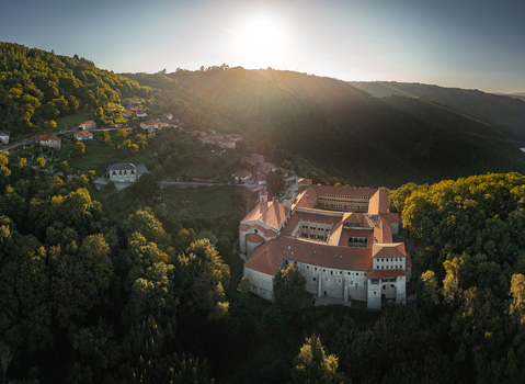 Aerial view of Monastery of Santo Estevo de Ribas de Sil in Ribeira Sacra featuring historic stone architecture and terracotta rooftops surrounded by forests in O Covelo Ourense Spain.